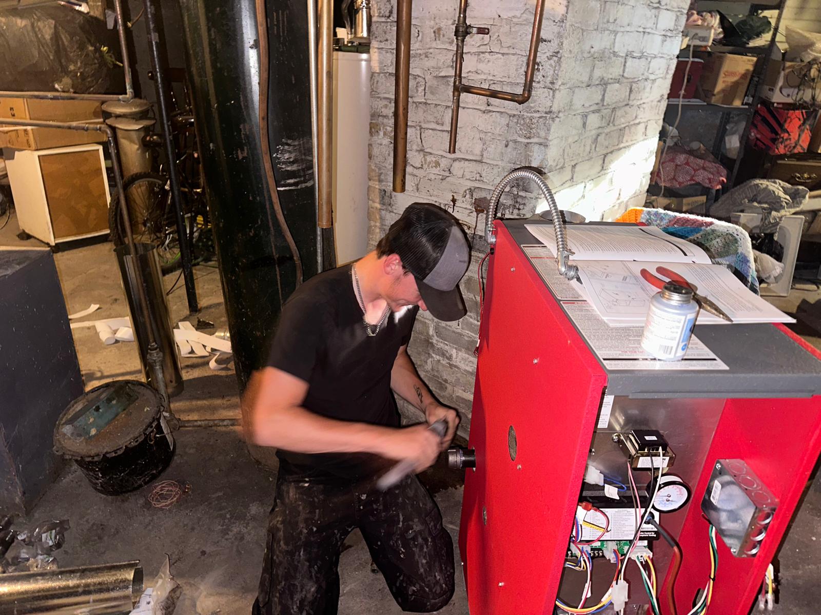 Man repairing red machinery in basement